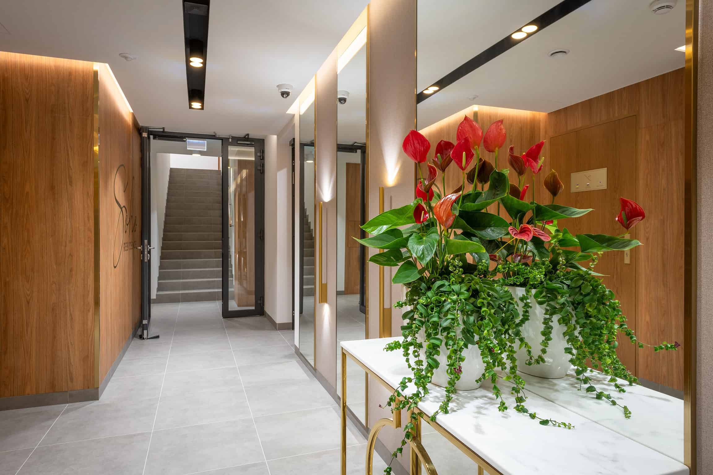 Hol w inwestycji Terra Casa S.A. - SoHo Residence II z nowoczesnym wystrojem i kwiatami.